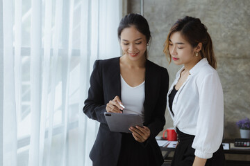 Two beautiful Asian women are meeting together in a company meeting room, meeting to discuss plans...