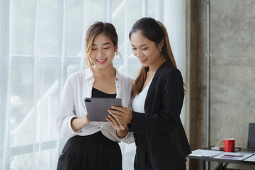 Two beautiful Asian women are meeting together in a company meeting room, meeting to discuss plans to develop the business to grow and follow the business plan. Business meeting idea.