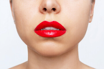 Cropped shot of a young beautiful caucasian woman with perfect lips with glossy red color lipstick isolated on a white background. Beauty and fashion concept