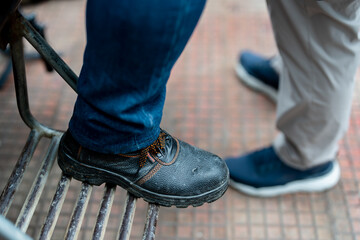 Close up Men's feet wearing leather shoes, which are safety shoes with steel inside to prevent injuries in construction site work.