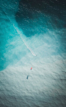 Aerial view of a person doing kitesurfing in open water.