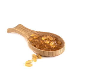 Omega 3 capsules in a wooden spoon on a white background