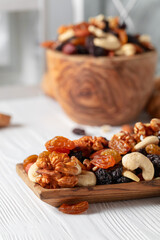 Mix of nuts and raisins on a white wooden table.