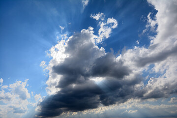 Blue sky and clouds. The sun's rays penetrating through the clouds