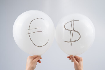 Woman holding two white balloons with dollar and euro symbols. 