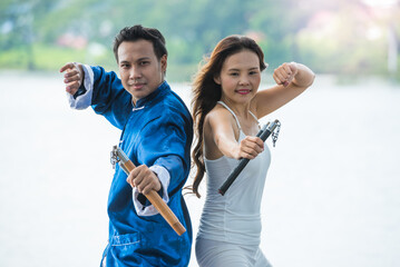 A couple of Young man and woman practicing Kung Fu or Martial art with Nunchaku for fighting...