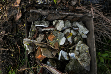 The badly damaged wooden crate is filled with rock debris and dried organic matter	