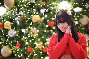 Beautiful Asian young woman with a red sweater with Christmas tree light