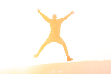 Young athletic man jumping high during sunset