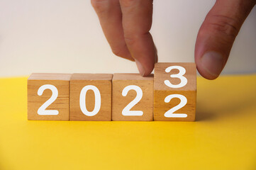 2023 happy new year symbol. Hand turning a cube from 2022 to 2023. Copy space. New year concept. - obrazy, fototapety, plakaty