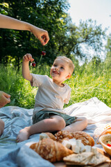 Boy child preschooler on a picnic. Smiles, eating cherries and enjoying summer.