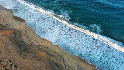 Aerial view of clean water ocean with waves crashing on sandy tropical beach 
