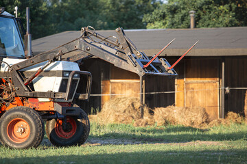 Work on the farm. A hay riser with a horse stable in the background