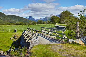 Landscape of wooden bridge in remote green countryside of Bodo in Nordland, Norway. Infrastructure and built crossing in eco meadow and environment fields. Toursim and exploring nature during the day