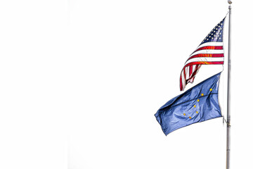Fototapeta premium American and Alaska Flags flying from pole on one side of image - isolated on white - Room for Copy