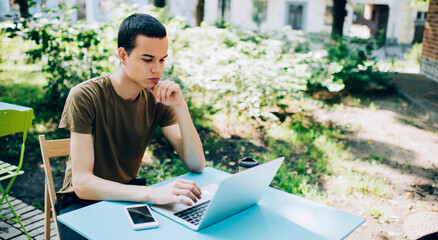 Wistful man typing on laptop during work