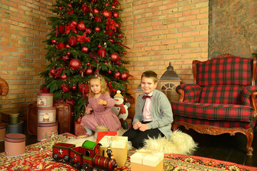 Obraz na płótnie Canvas Happy cute kids, brother and little sister in a festive interior for Christmas. Children's entertainment. Present. Family traditions. New Year concept.
