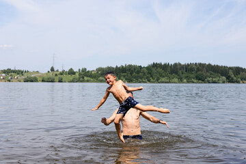 father and son swim together in a river pond