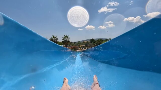 European girl going of a blue waterslide in the summer