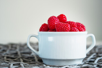 Fresh raspberries in the white bowl with copy space