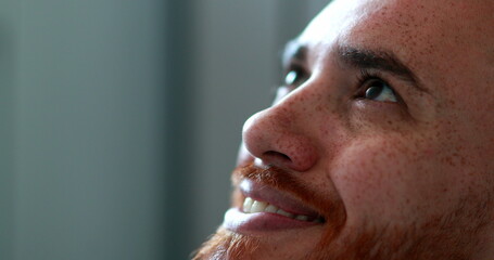 Fototapeta premium Man opening eyes looking up smiling, close-up redhead face man looks up