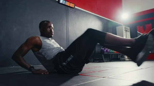 Work out black man swing his legs to do crossfit exercise and weight lifting inside of fitness gym. Body workout strength and firm abs muscle for physical body health.