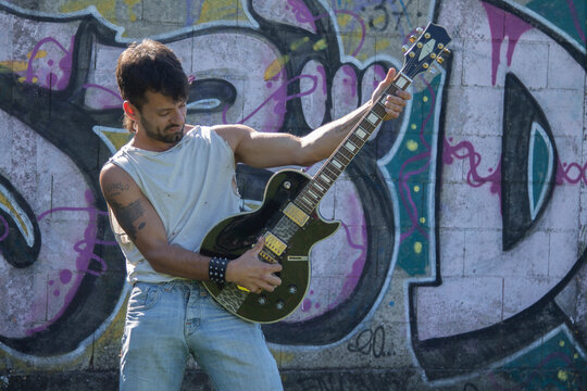 Young Man With Electric Guitar On Graffiti Wall