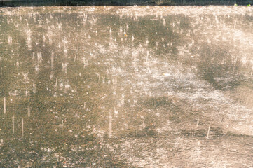 A defocused shot of a summer downpour. A rainstorm on a city street. A summer thunderstorm. Falling large raindrops. Selective focus. Motion blurred. Noise, grain effect.