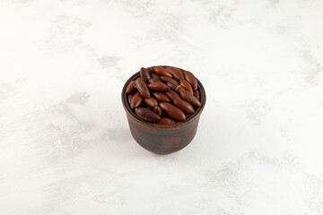 Baru nuts in ceramic cup on grey textured background, selective focus. Trendy superfood. Baru seeds...