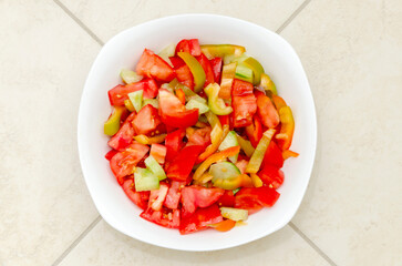 White plate with fresh tomato and sweet pepper salad. Close-up