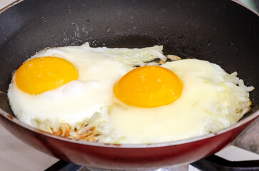 Fried eggs with onions in a pan. Close-up
