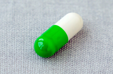 White and green capsule with contents, food supplements or drugs on a gray background. Medical concept. Selective focus. Close-up. Macro.