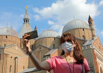 Young woman takes a selfie with her smartphone at herself and at the Basilica of Santo Antonio in...