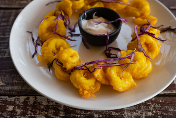 Delicious seafood meal of deep-fried golden squid rings on an platter with copy space on rustic...