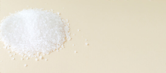 Banner. Handful white sea salt on a creamy background. Rough texture. Salt is suitable for cooking and beauty treatments. Horizontal orientation. copy space