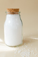 Glass jar of white sea salt. Rough texture. Salt is suitable for cooking and beauty treatments. Vertical orientation.