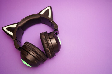 Black wireless headphones isolated on purple background. A cosplay accessory. Wireless gaming...