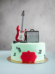 Musical themed cake with a guitar on top as a decoration. Sweet food for the musician's birthday. A...