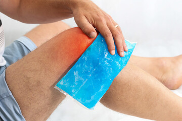 Man using cool gel pack on a swollen injured knee with Color Enhanced skin with red spot indicating...