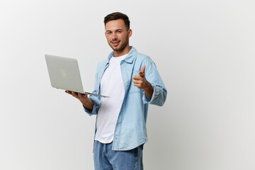 Smiling handsome IT professional man in casual basic t-shirt point finger at camera hold laptop posing isolated on over white studio background copy space. Electronics repair. I choose you concept