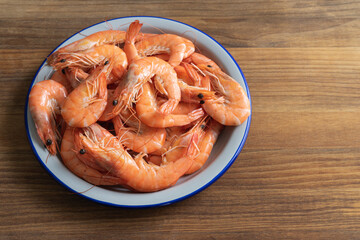 Dish of cooked shrimp on a wooden base. Copy space.