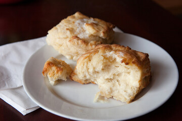 Biscuit Torn Open on a Simple White Plate with Melted Butter on Top