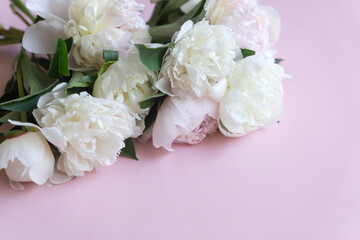 Cup of coffee and white peonies on a wooden background. Top view, copy space.