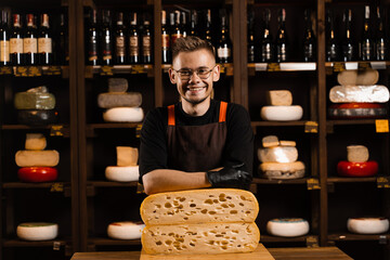 Professional cheese sommelier in food shop. Worker of cheese store with limited maasdam natural aged.