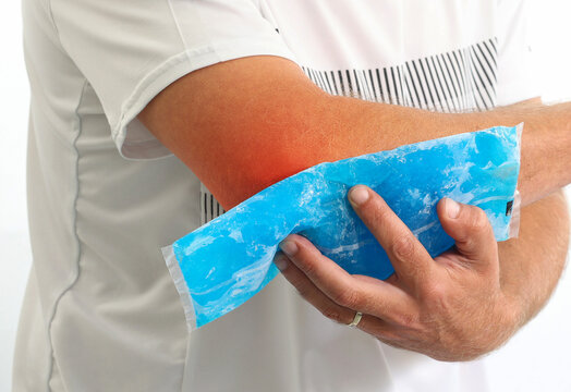Injured Man using reusable ice gel packs his elbow, medical first aid after accident. Man pain elbow with color Enhanced skin with red spot indicating location of the pain isolated on white. 