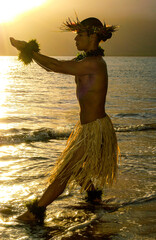 Male Hula Dancer in offering pose into the sunset. 
