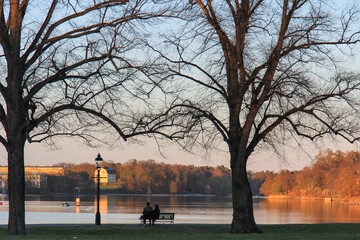 Silhouette of a couple sitting on a bench at the lakeside at sunset