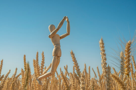 Prayer for Ukraine. The wooden figurine of a man cries out to God against the background of the sky and wheat ears.