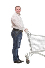 Full length side view of handsome young man standing with shopping trolley and looking at camera