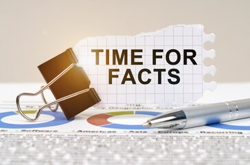 On the table are reporting charts, a pen, in a clip paper with the inscription - Time for Facts